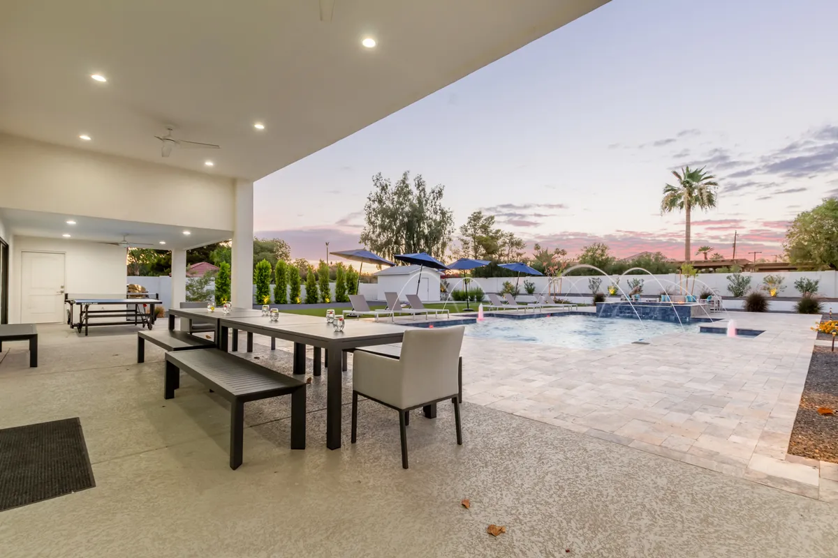A tranquil backyard scene showcasing a sparkling swimming pool, inviting outdoor dining area, cushioned seating, and beautifully landscaped gardens. The atmosphere is serene yet social, perfect for relaxing after a day on the golf course or enjoying an al fresco meal with friends and family.