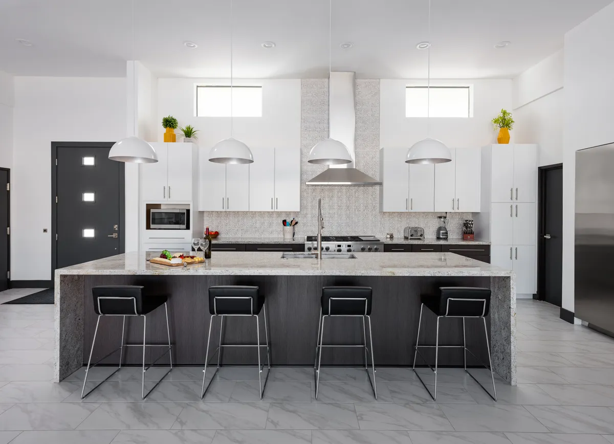 A stylish chef’s kitchen featuring a generous kitchen island with marble countertop, gleaming stainless steel appliances, and elegant pendant lights overhead. The space is designed for both culinary adventures and social gatherings, balancing functionality and luxury.