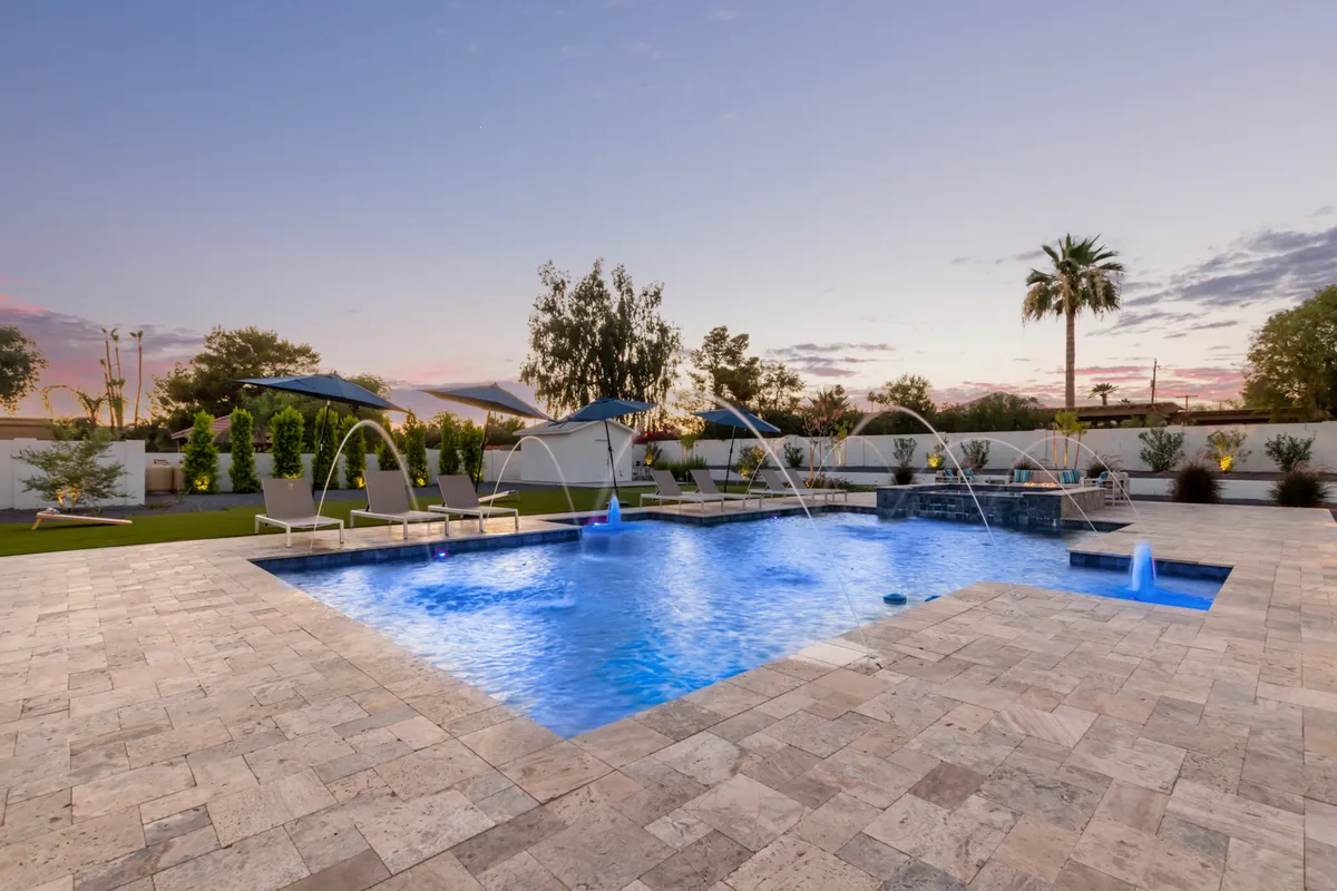 This exterior image features a stunning swimming pool surrounded by sun loungers and palm trees, with gentle water features and space for both relaxation and play. The tranquil setting highlights resort-style amenities and outdoor entertainment options.
