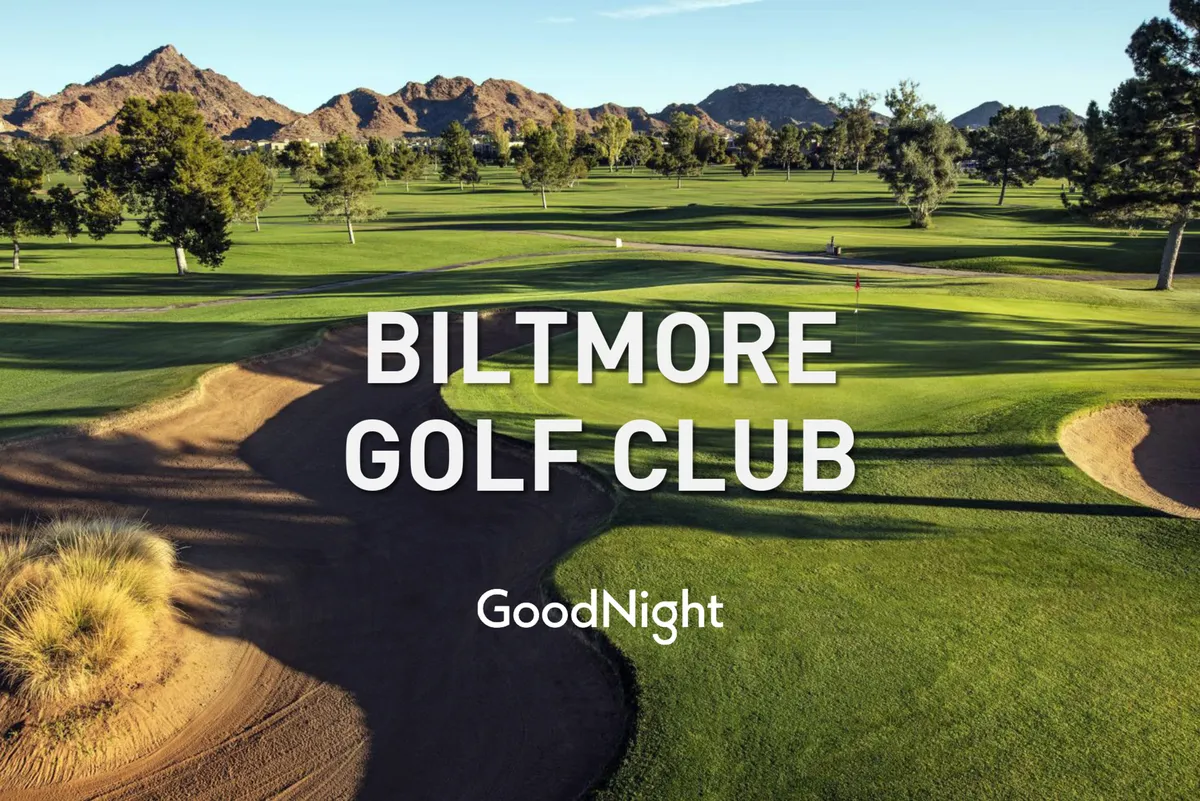 A sweeping view of a manicured golf course framed by lush green fairways, sand traps, and a mountainous backdrop. The scene captures the serenity and luxury associated with golf in the Scottsdale area, with the expansive course inviting both play and relaxation. The lighting suggests a late afternoon or evening, ideal for catching sunset views after a day on the greens.